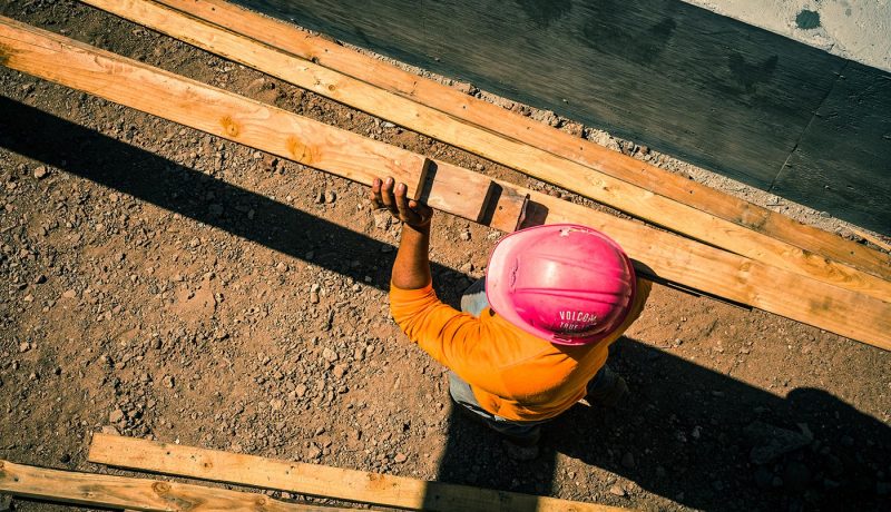 construction-site-with-worker-carrying-lumber_t20_7JOngv